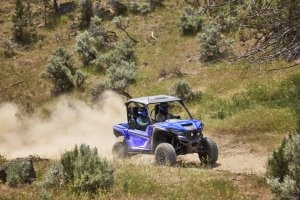 Wolverine RMAX on a trail, grass in the distance